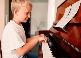 Menino tocando piano, foto Best Digital Piano Guides